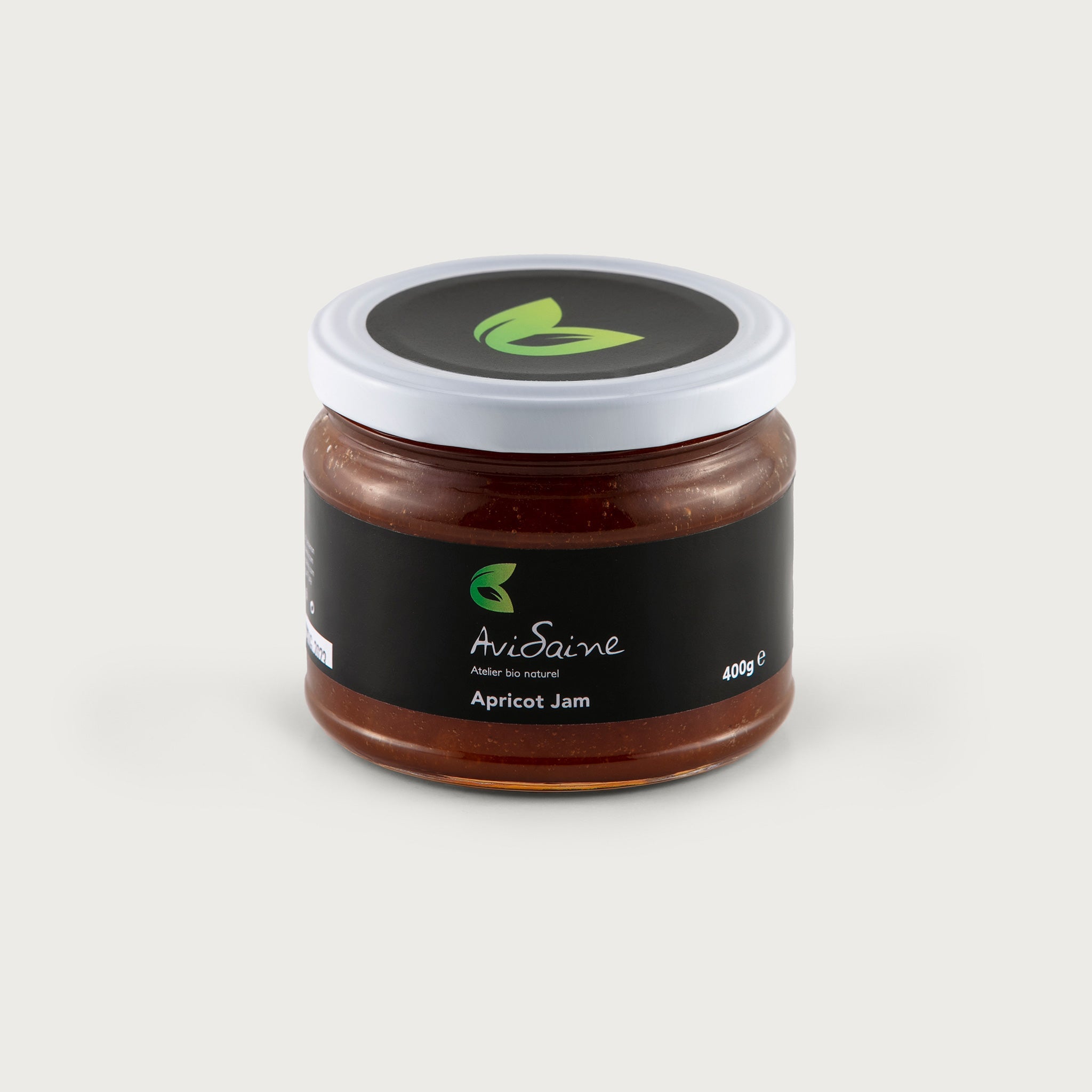 A clear 14 oz. jar shows the rich honey colored Apricot jam with particulates. The label is black and features the AviSaine logo in green.