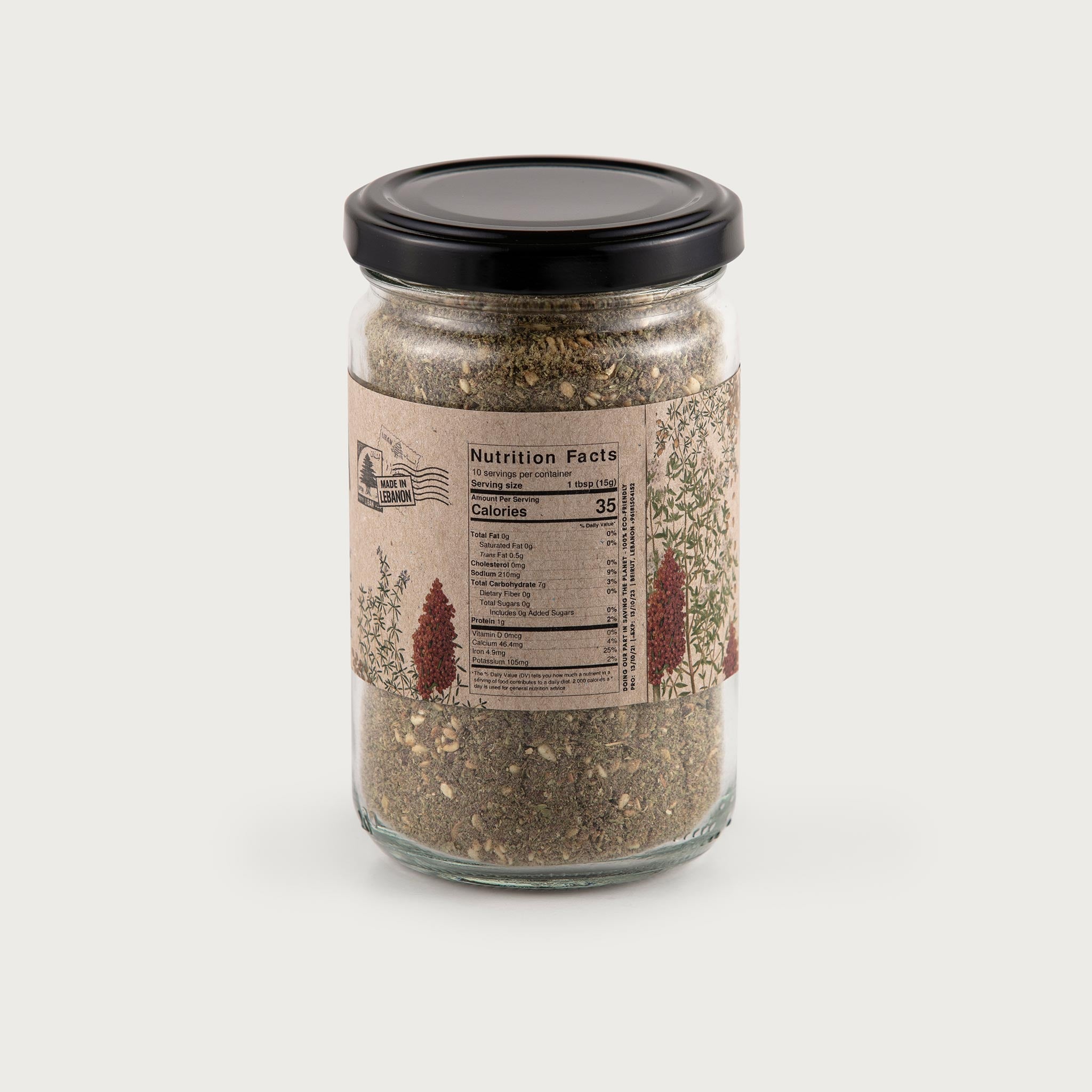 This clear jar of Traditional Za'atar showcases the beautiful ingredients inside. You can see the herbs, beautifully sage green, brown, and dried. The label is kraft brown in color and features illustrations of the herbs inside. The label reads: Traditional Za'atar with ingredients dried wild thyme, pure sumac, salt, roasted sesame seeds. Contains sesame, gluten free, vegan, and store in a dry place. There is a QR code on the front.